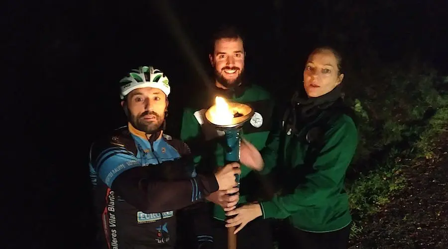 Ciclistas e membros do CB Xallas levando o Familia xalleira co facho da esperanza na marcha Nunca Caminaras soa