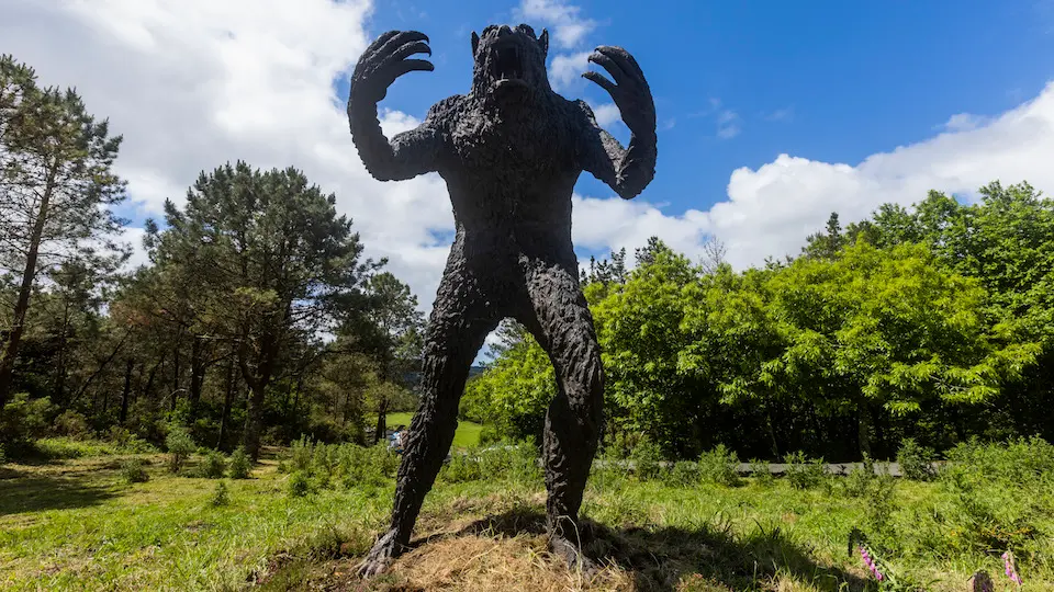 A estatua representa ao home lobo que no século XV se lle apareceu a un bispo armenio que decidiu facer o Camiño desde Santiago de Compostela a Fisterra.
É a primera escultura dedicada a un home lobo en España.