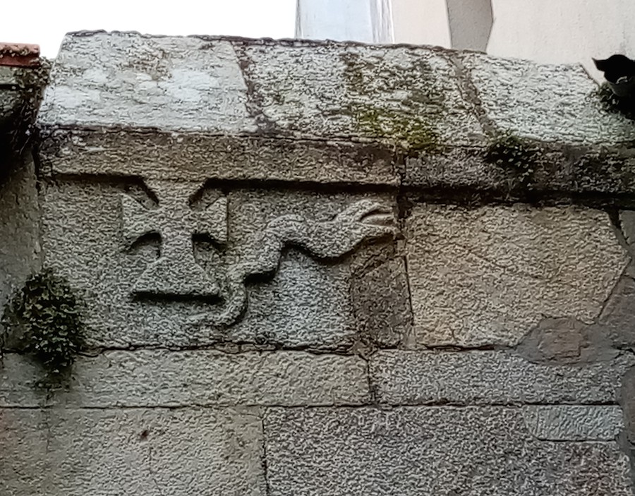 A cruz e a serpe gravadas nun muro lindeiro coa fachada da igrexa parroquial de Malpica